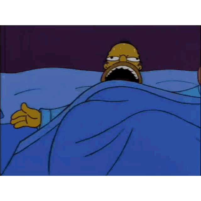 homer simpson is laying in a bed with his mouth open .