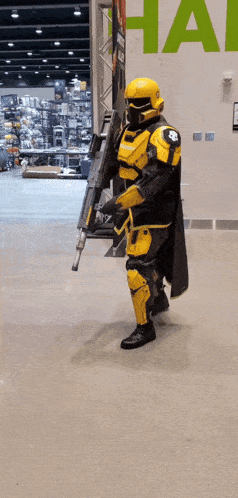 a man in a yellow armor holding a gun in front of a sign that says hall