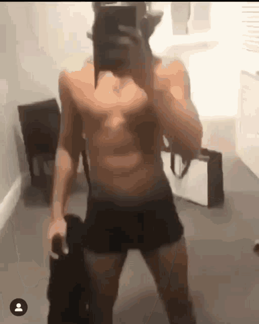 a man without a shirt is taking a picture of himself in a mirror .
