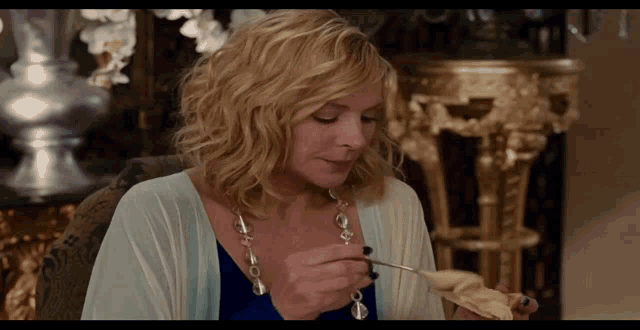 a woman in a blue dress is eating a piece of food