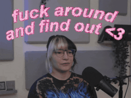 a woman with glasses stands in front of a microphone with the words fuck around and find out above her