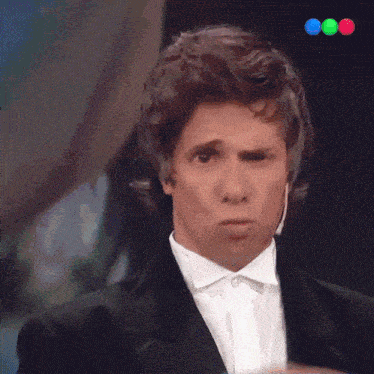 a man in a tuxedo is pointing at the camera