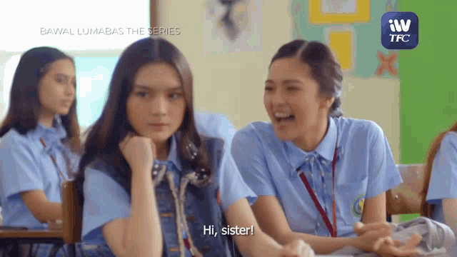 a group of girls are sitting in a classroom and one of them says hi sister