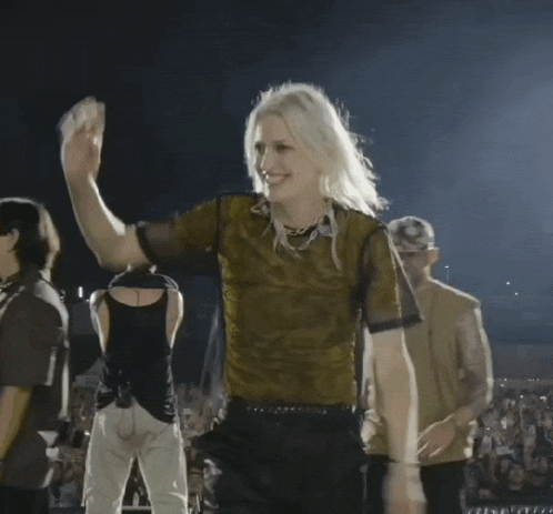 a woman in a green shirt is dancing in front of a crowd