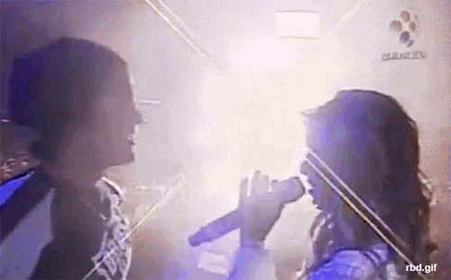 a woman is singing into a microphone while another woman is playing a violin .