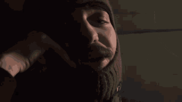 a close up of a man wearing a hooded sweater with a purple x on the front