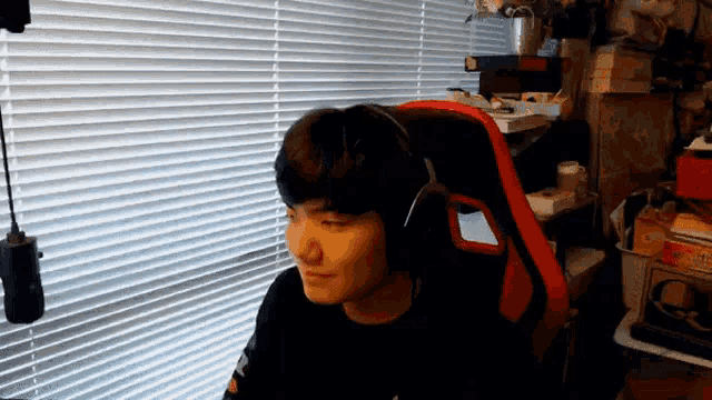 a young man wearing headphones is sitting in front of a window in a room .