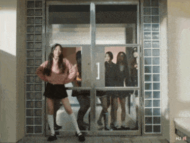 a girl in a pink sweater is standing in a doorway with a group of girls behind her