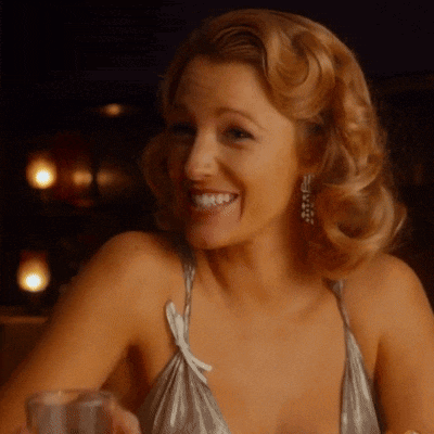 a woman in a silver top is smiling and holding a glass of water
