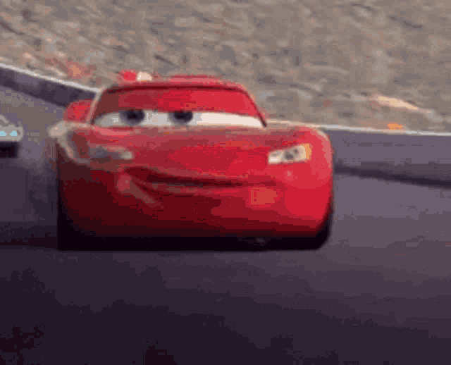 a red car from the movie cars is driving down a track .