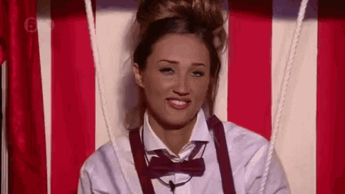 a woman is wearing a bow tie and suspenders and smiling .