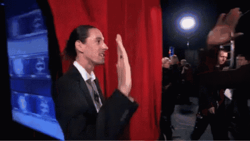a man in a suit is giving a high five to another man