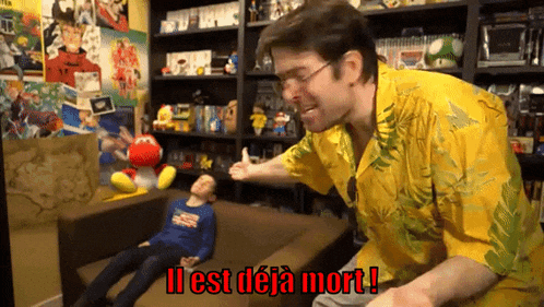 a man in a yellow shirt is standing next to a boy who is laying on a couch and says il est deja mort !