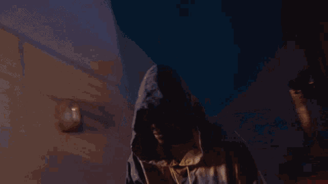 a man in a hooded sweatshirt stands in a dark room