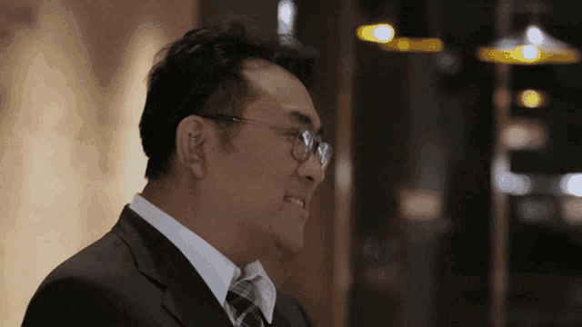 a man wearing glasses and a suit smiles