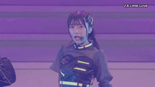 a girl with a microphone on a stage with a little love written below her