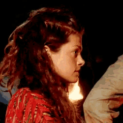 a woman with long red hair is standing in the dark