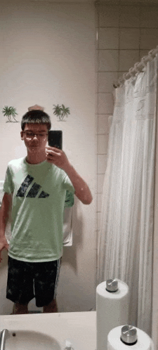 a boy is taking a selfie in a bathroom mirror .