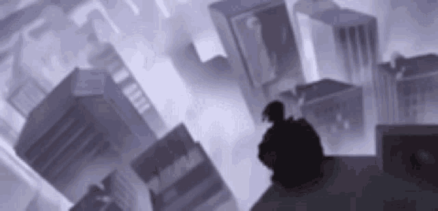 a silhouette of a man standing on top of a building in a city .