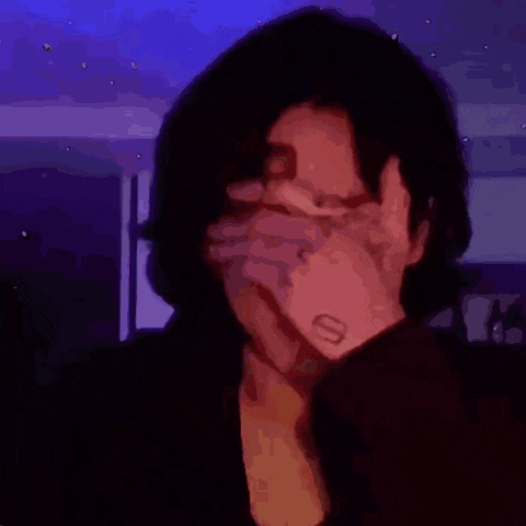 a woman covering her face with her hand with a smiley face tattoo