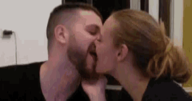 a man and a woman are kissing each other in a room .