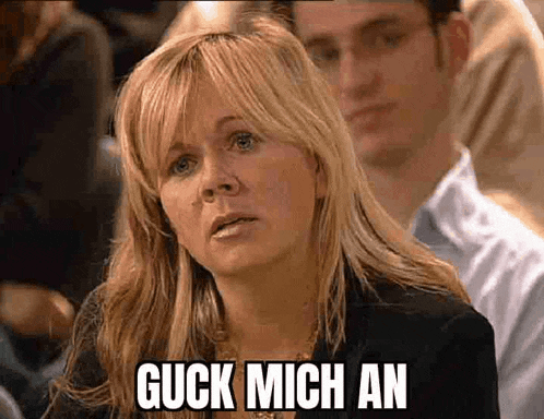 a woman is sitting in front of a man with the words guck mich an on her face