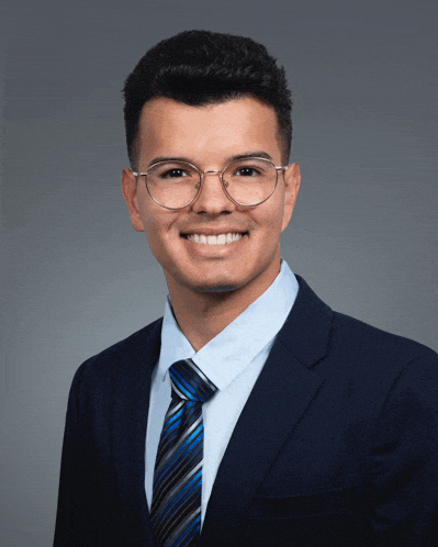 a man wearing glasses and a blue suit smiles for the camera