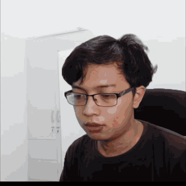 a young man wearing glasses and a black shirt