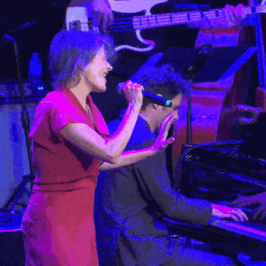 a woman sings while a man plays a piano
