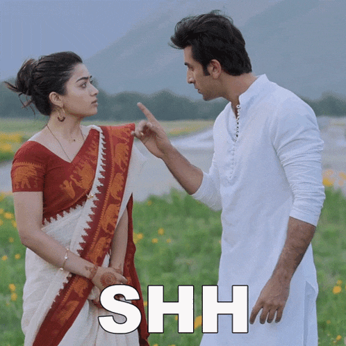 a man and a woman are standing in a field and the word shh is on the bottom