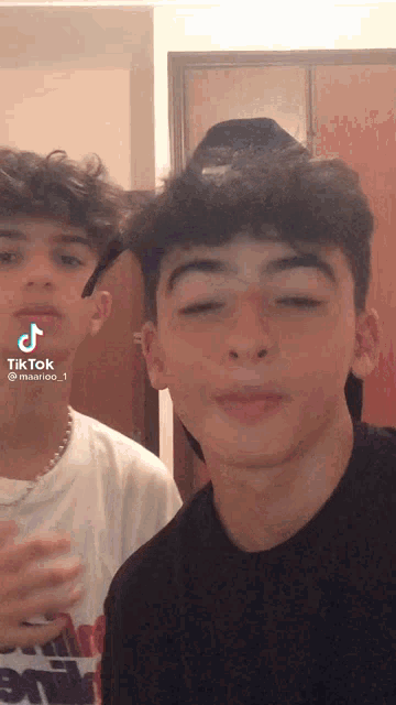 two boys are standing next to each other and one of them is wearing a white shirt with the word army on it
