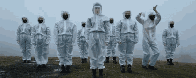 a group of people wearing protective suits and masks stand in a line