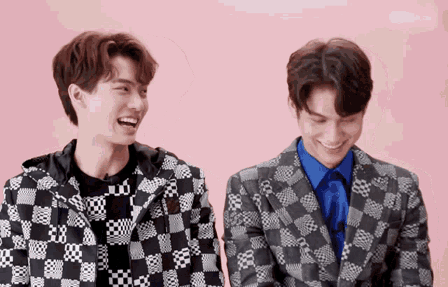 two men wearing plaid suits are laughing and smiling