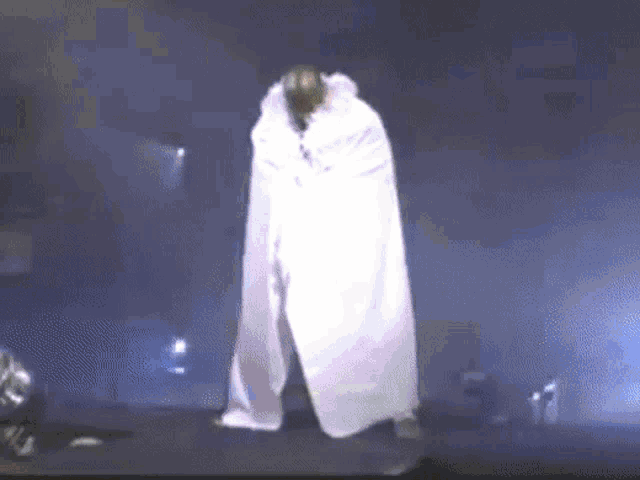 a person in a white cape is standing in the dark