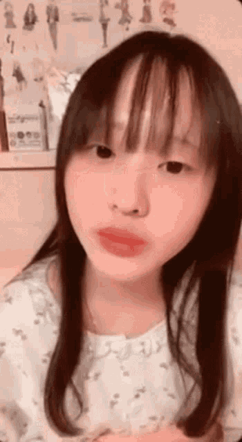 a young girl with long hair and bangs is making a funny face with her mouth open .