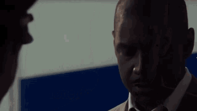 a man in a suit is talking to another man and says do me a favour just