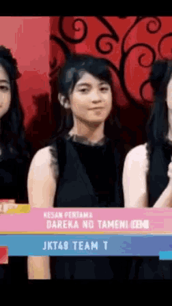 a girl in a black dress is standing next to two other girls .
