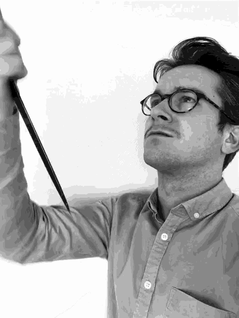 a man wearing glasses and a button down shirt is holding a knife