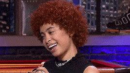 a woman with red curly hair is smiling and wearing a black shirt