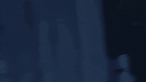 a statue of a man with a sword is in a dark room with a blue background