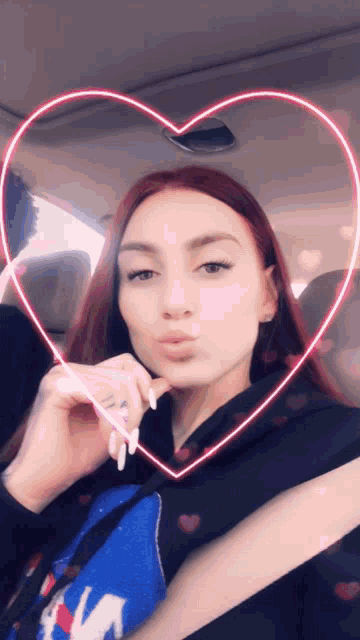 a woman with red hair is sitting in a car with a heart shaped light behind her