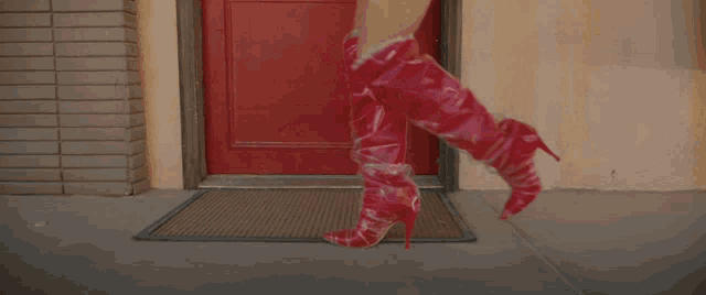 a woman wearing red boots is standing in front of a door