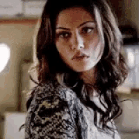 a woman with long brown hair is wearing a sweater and looking over her shoulder .