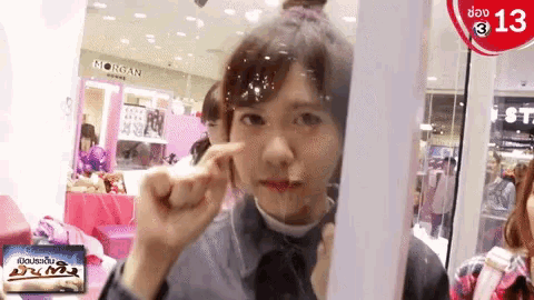 a woman is looking at herself in a mirror in front of a sign that says morgan