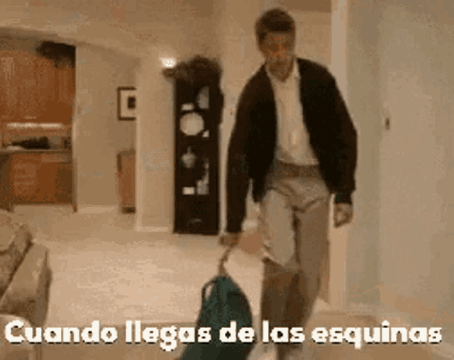 a man is pulling a suitcase in a living room with the words cuando llegas de las esquinas written on the bottom