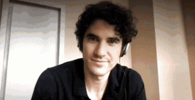 a man with curly hair is wearing headphones and a black shirt