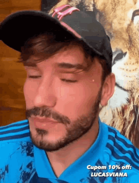 a man with a beard wearing a hat and a blue shirt with the words cupom 10 % off lucasviana on the bottom