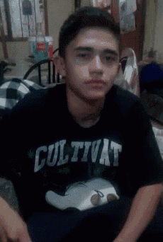 a young man wearing a cultivat shirt sits in a room