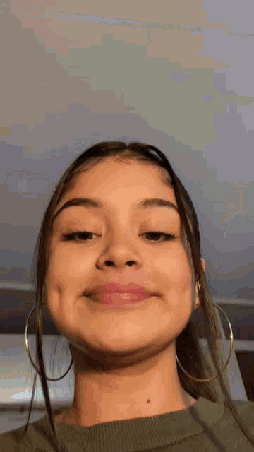 a woman wearing hoop earrings is making a funny face .