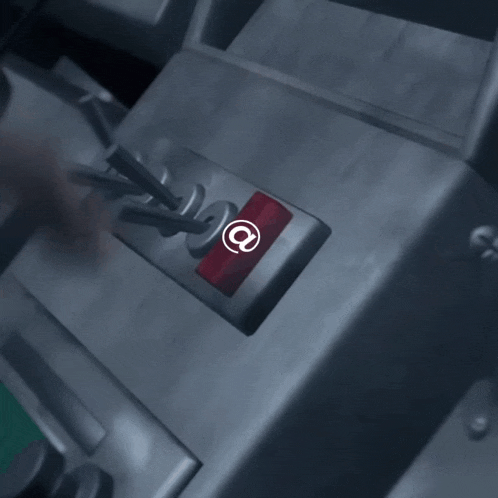 a person is pressing a red button with an at symbol